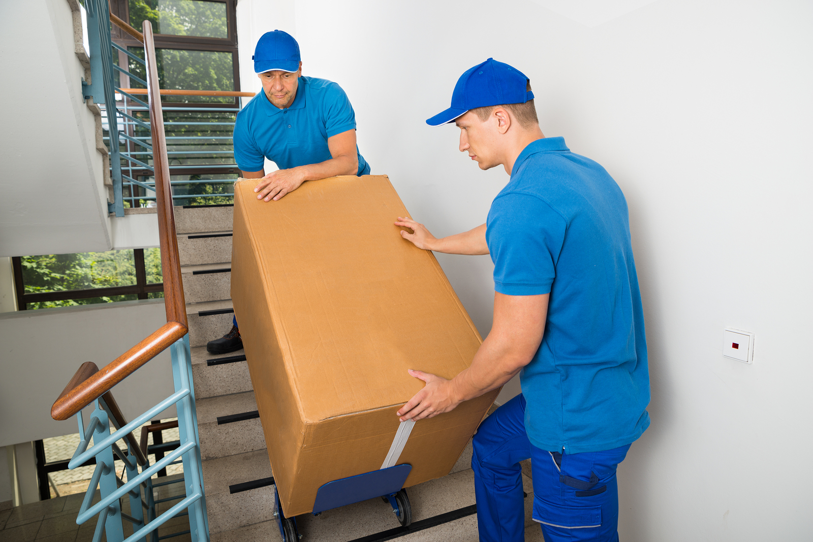 Two Movers With Box On Staircase men moving a box down the stairs